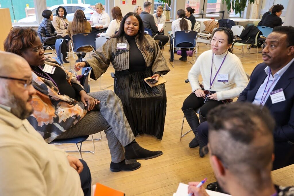 A diverse group of students sits in a circle, actively engaged in discussion during a workshop.