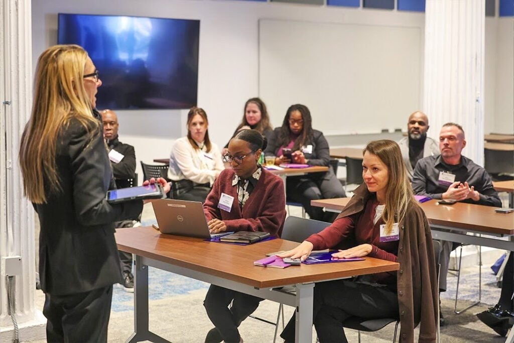 Professional training session with a presenter addressing attendees at tables.
